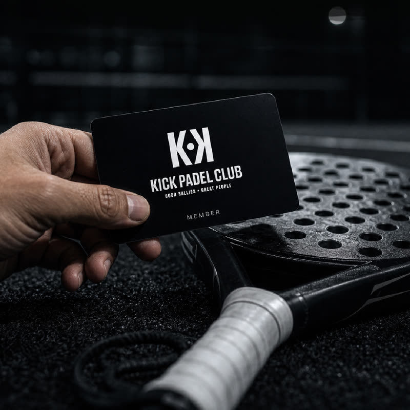 Close-up of a hand holding a black Kick Padel Club membership card, resting on a padel racket